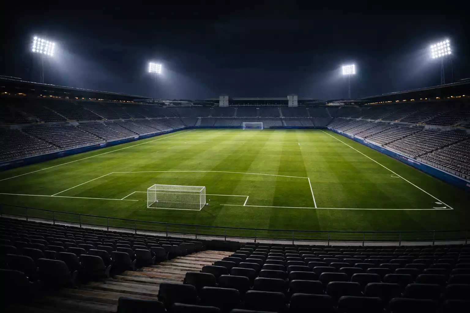 Estadio de fútbol europeo iluminado de noche con el césped brillante bajo los focos