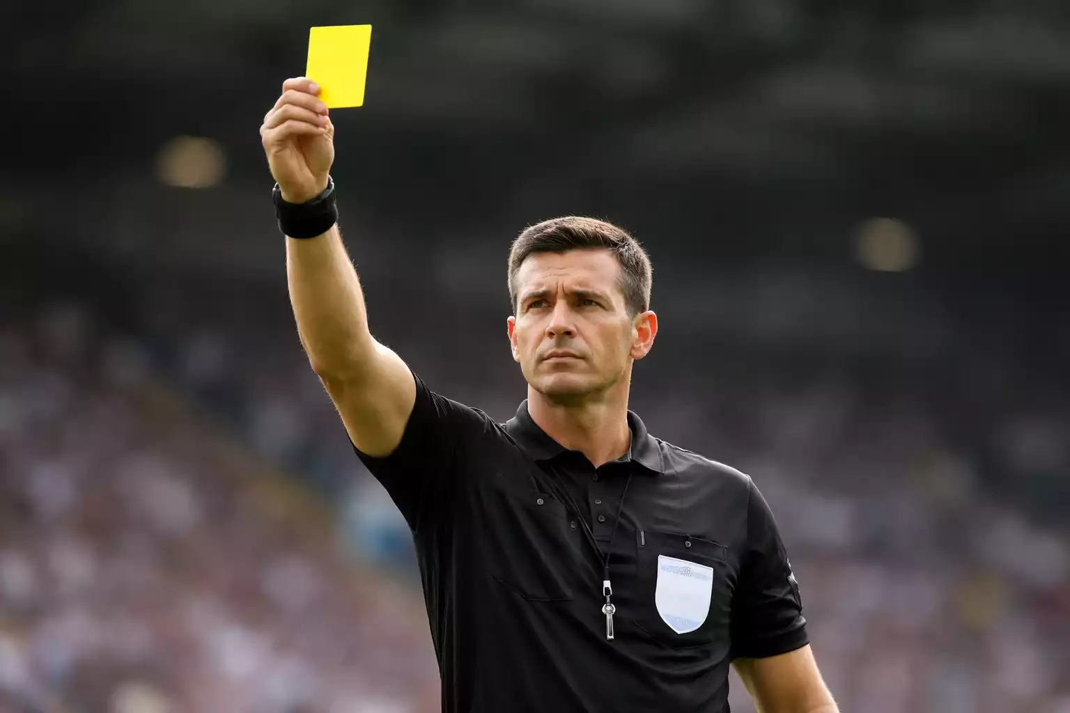 &Aacute;rbitro de f&uacute;tbol mostrando tarjeta amarilla durante un partido
